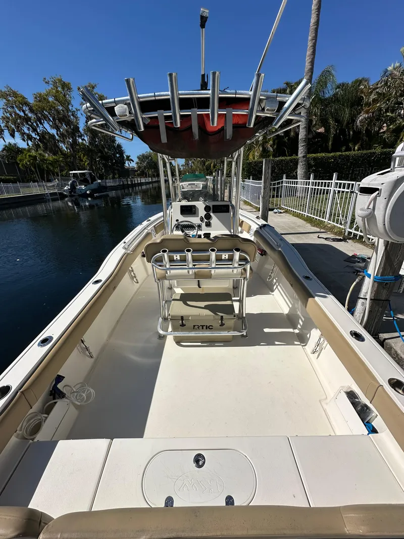 Slide: The Image of 2019 Key West 239 FS boat docked by a canal, featuring a spacious deck and T-top. - 8