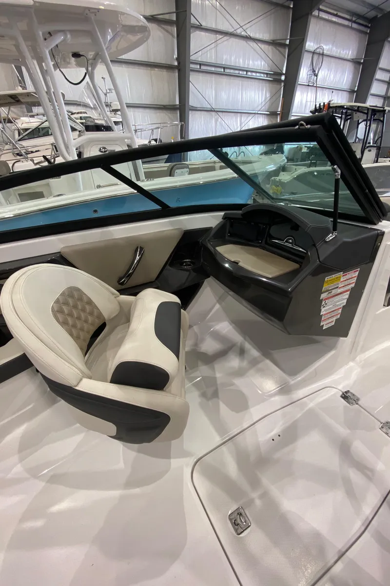 Slide: The Image of 2024 Monterey 215SS boat interior with captain's chair and dashboard in a showroom. - 12