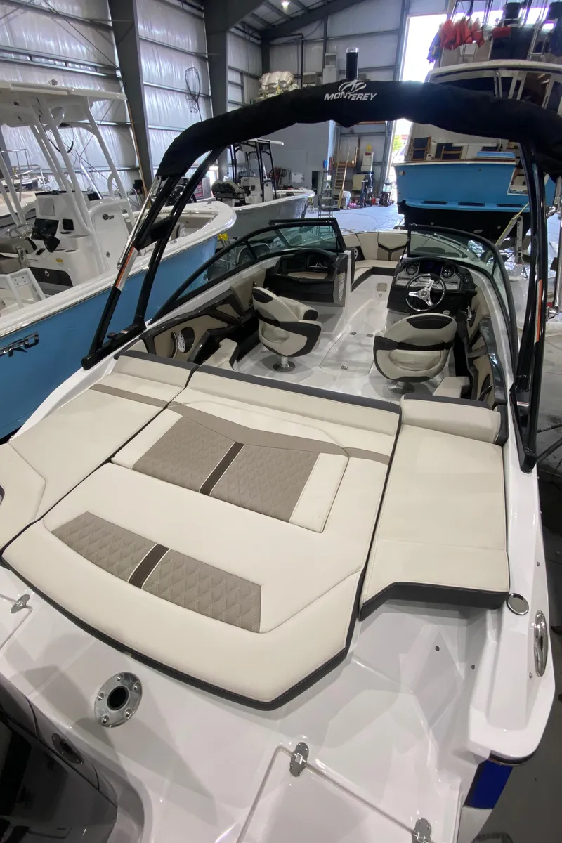 Slide: The Image of 2024 Monterey 215SS boat with spacious seating and modern design in a showroom. - 13