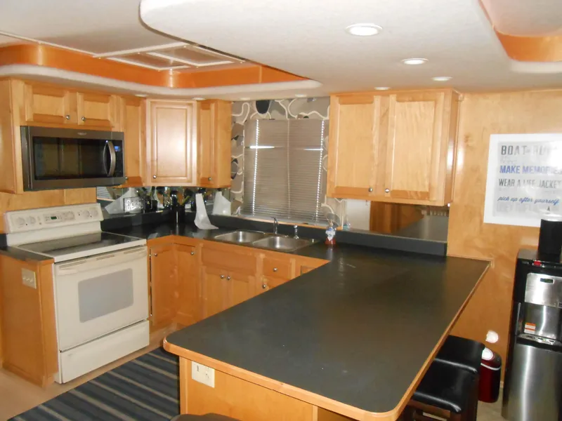 Slide: The Image of Modern kitchen in a 2000 Sumerset 7016 houseboat with wooden cabinets and black countertops. - 11