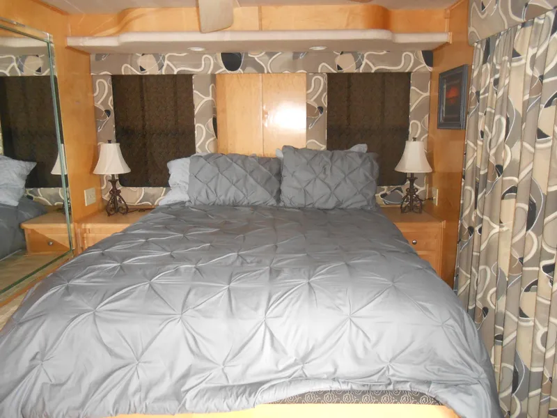 Slide: The Image of Sumerset 7016 2000 model bedroom with gray bedding and decorative curtains. - 3