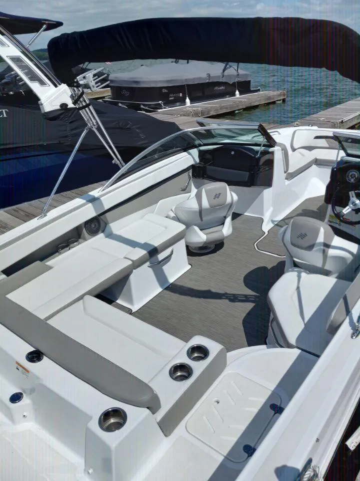 Slide: The Image of 2022 Four Winns HD2 boat interior with seating and cup holders at a dock. - 11