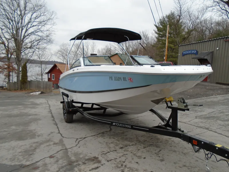 Slide: The Image of 2022 Four Winns HD2 boat on trailer near lake and buildings. - 2