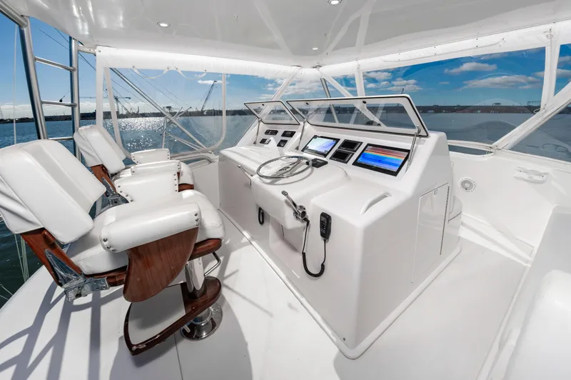 Slide: The Image of 2005 Viking Convertible yacht helm with modern controls and white seating, overlooking the ocean. - 14