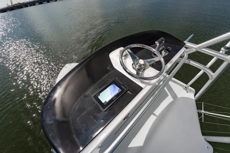 Slide: The Image of 2005 Viking Convertible boat helm with steering wheel and navigation screen on calm water. - 23