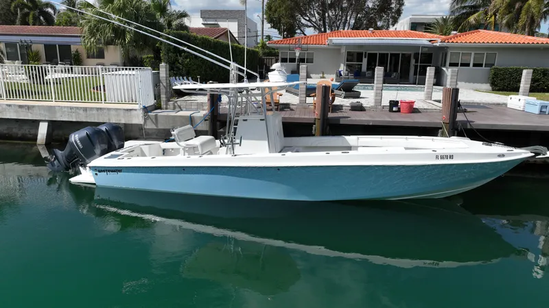 Slide: The Image of 1987 Whitewater 32 Open boat docked by waterfront homes. - 0