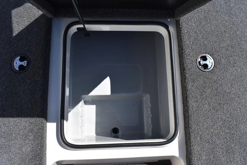 Slide: The Image of 2024 Triton 179 TrX boat storage compartment with gray carpeted interior. - 12