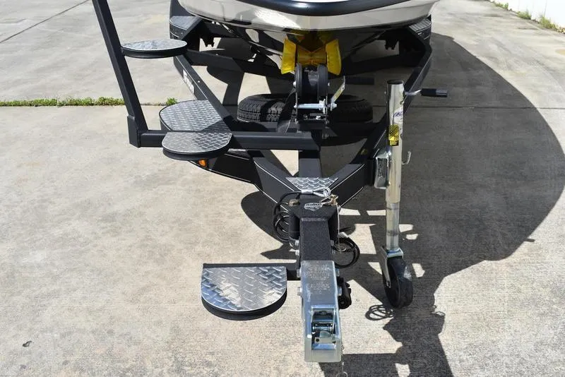 Slide: The Image of 2024 Triton 179 TrX boat trailer with metal steps and hitch on concrete surface. - 8