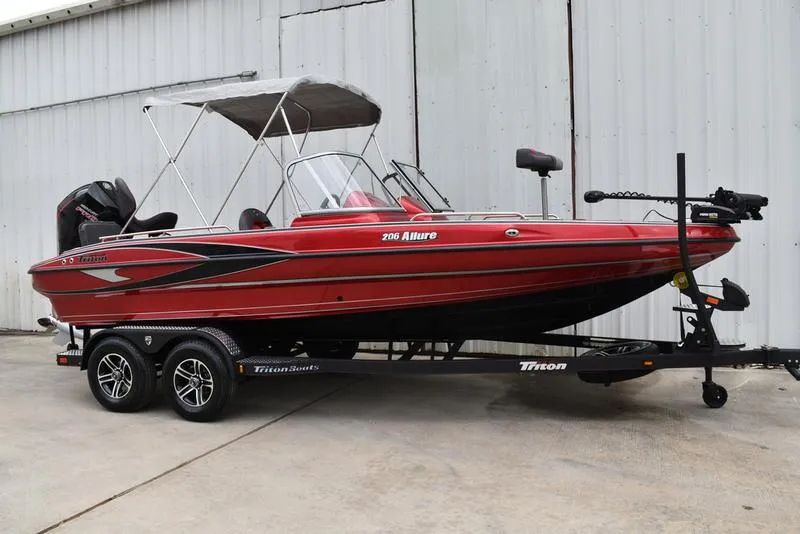 Slide: The Image of 2024 Triton 206 Allure red fishing boat on trailer with canopy. - 3