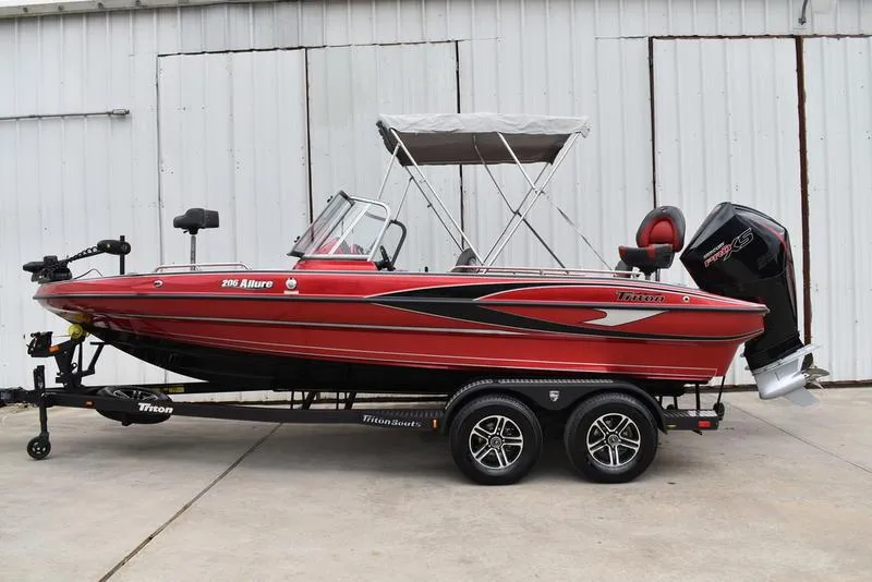 Slide: The Image of 2024 Triton 206 Allure red fishing boat on trailer with outboard motor. - 4