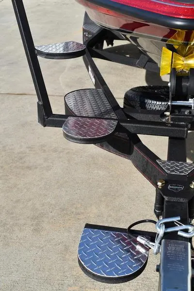 Slide: The Image of 2024 Triton 179 TrX boat trailer with metal steps and hitch on concrete surface. - 10