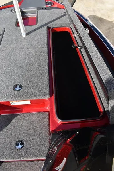Slide: The Image of 2024 Triton 179 TrX boat storage compartment with open lid, featuring red and gray interior. - 17