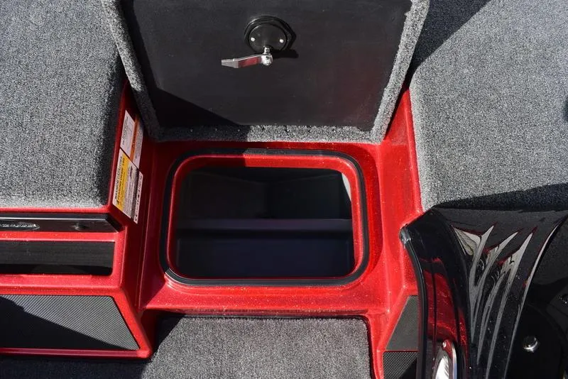 Slide: The Image of 2024 Triton 179 TrX boat storage compartment with red trim and carpeted interior. - 19
