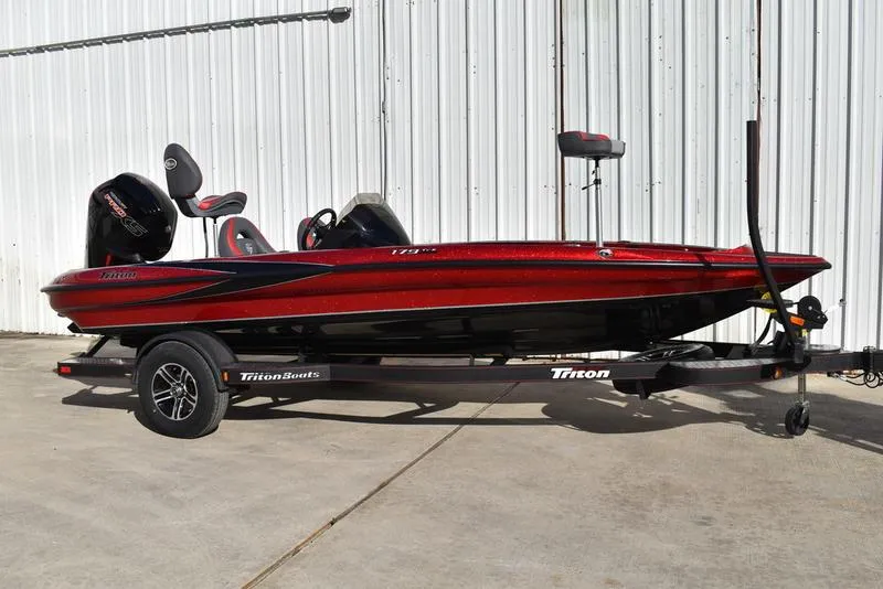 Slide: The Image of 2024 Triton 179 TrX bass boat on trailer, red and black design, parked outdoors. - 4