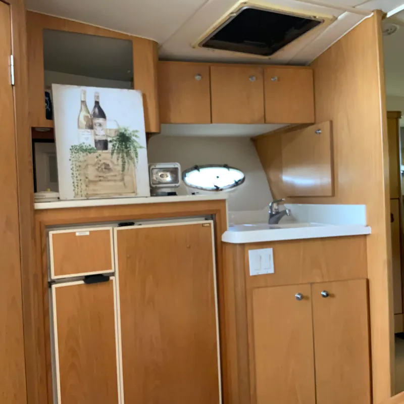Slide: The Image of Compact kitchen area in a 2000 Tiara Sport 35 Open boat with wooden cabinets and a small sink. - 23