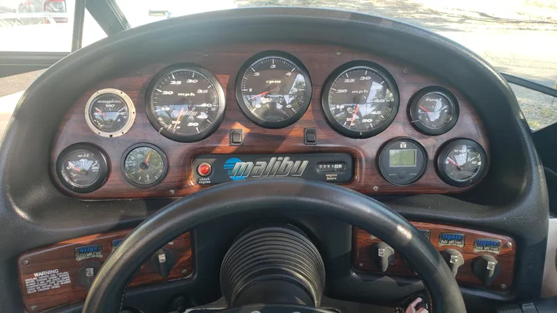 Slide: The Image of Dashboard of a 1998 Malibu Sunsetter VLX boat with gauges and controls. - 10