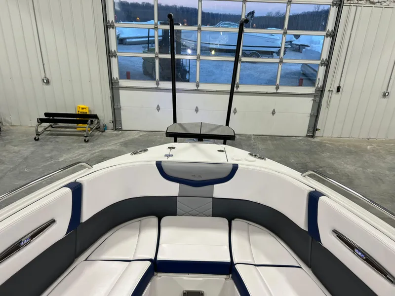 Slide: The Image of 2021 Chaparral 287 SSX boat interior with white and blue seating in a garage setting. - 10