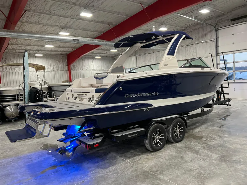Slide: The Image of 2021 Chaparral 287 SSX boat in a showroom, featuring sleek design and blue hull. - 2