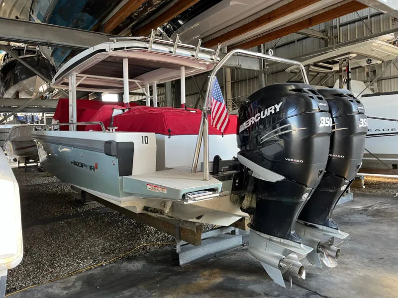 Slide: The Image of 2019 Axopar 37 Sun Top with twin Mercury 350 engines in a boat storage facility. - 13