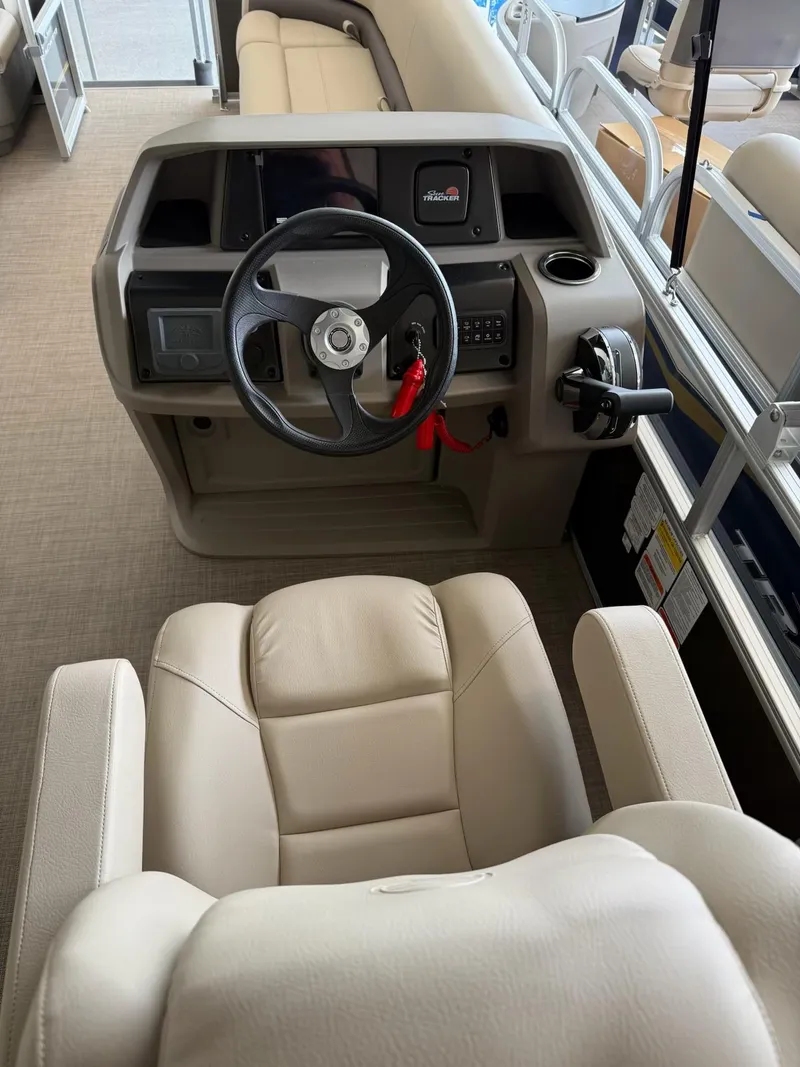 Slide: The Image of 2024 Sun Tracker Party Barge 18 DLX helm with beige seating and steering wheel. - 6