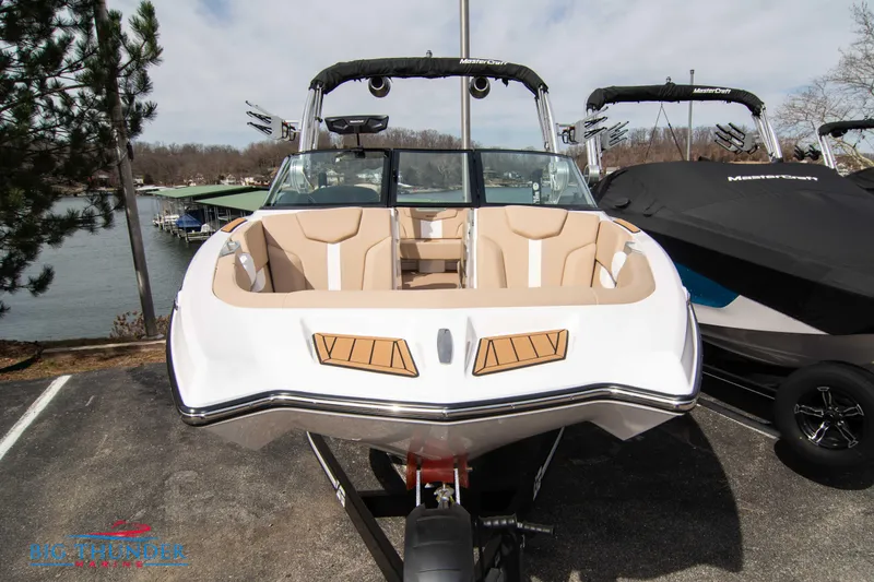 Slide: The Image of 2024 MasterCraft XT24 boat with tan interior, docked near a lake. - 3