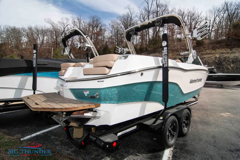 Slide: The Image of 2024 MasterCraft XT24 boat on trailer, teal and white, rear view. - 5