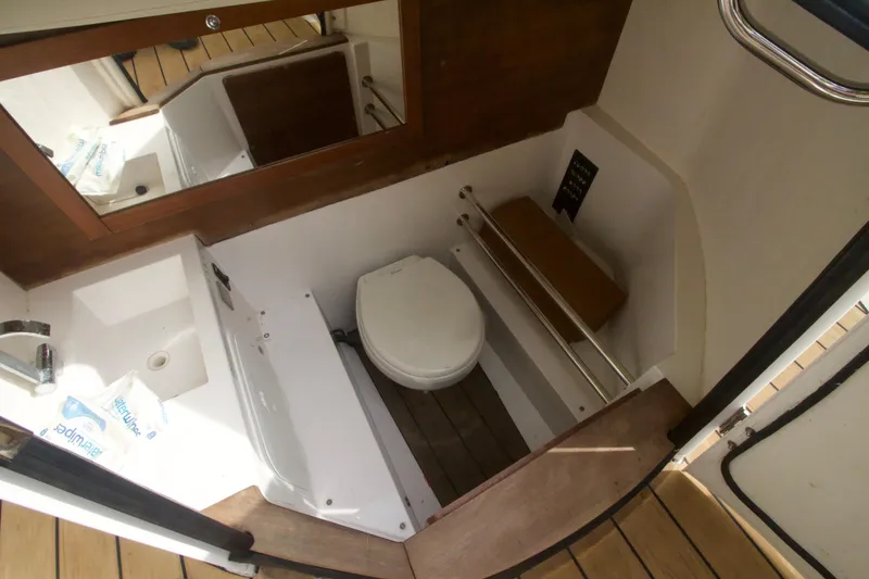 Slide: The Image of 2016 Axopar 28 TT boat bathroom with toilet, sink, and wooden flooring. - 13