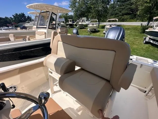 Slide: The Image of 2025 Scout 240 XSF boat interior with beige seating and steering wheel, parked outdoors. - 7