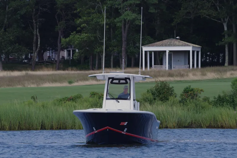 Slide: The Image of 2024 Regulator 28 boat on water near grassy shoreline and pavilion. - 10