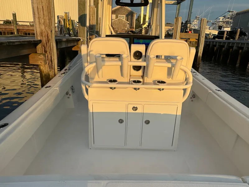 Slide: The Image of 2024 Regulator 28 boat interior with dual seats and storage, docked at marina. - 16