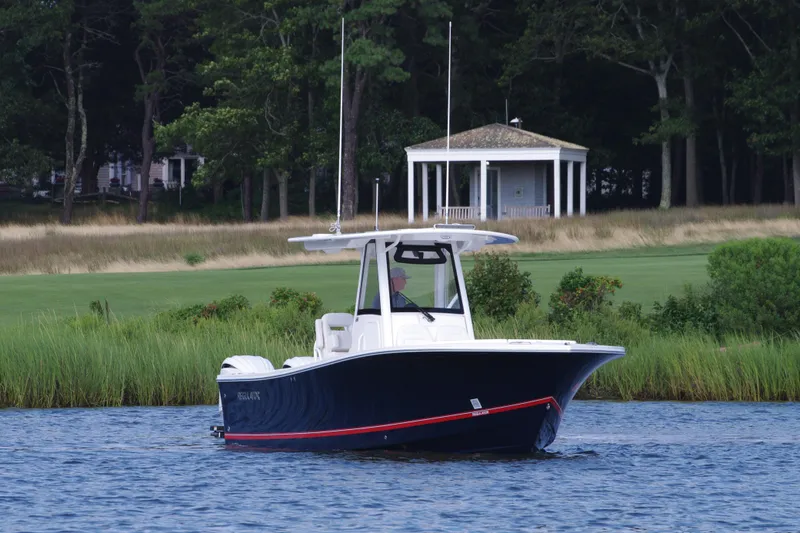 Slide: The Image of 2024 Regulator 28 boat on a serene lake with lush greenery. - 2