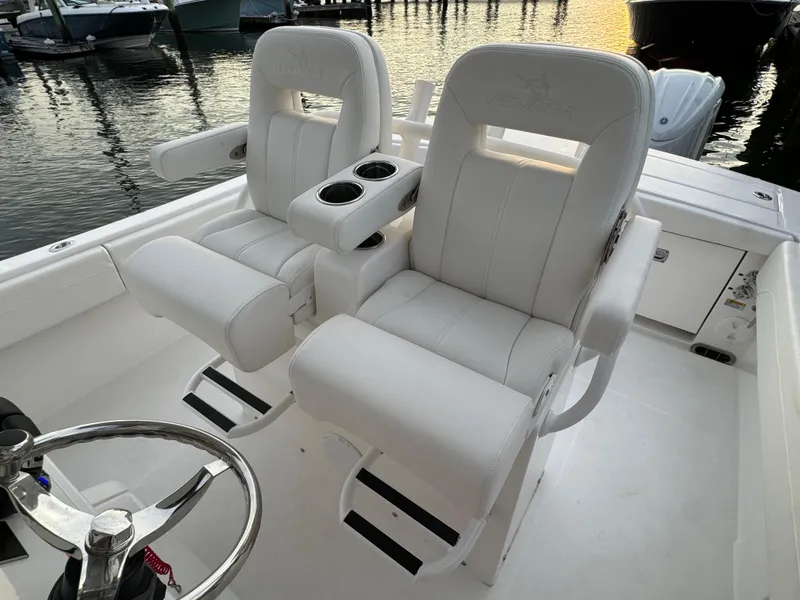 Slide: The Image of 2024 Regulator 28 boat with white cushioned seats and cup holders at a marina. - 23