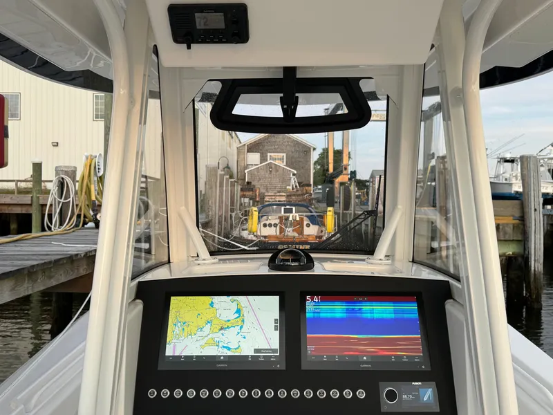 Slide: The Image of 2024 Regulator 28 boat dashboard with navigation screens at a marina dock. - 27