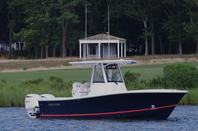 Slide: The Image of 2024 Regulator 28 boat on water near a gazebo and lush greenery. - 3