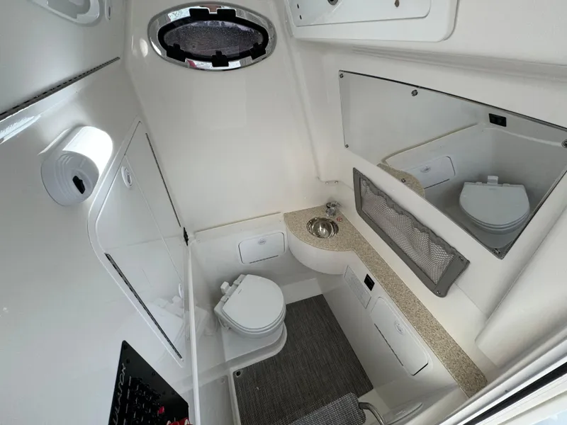 Slide: The Image of 2024 Regulator 28 boat interior with compact bathroom, sink, and mirror. - 44