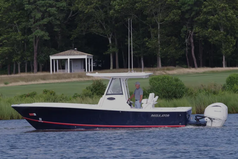 Slide: The Image of 2024 Regulator 28 boat cruising on a lake with a wooded shoreline. - 8