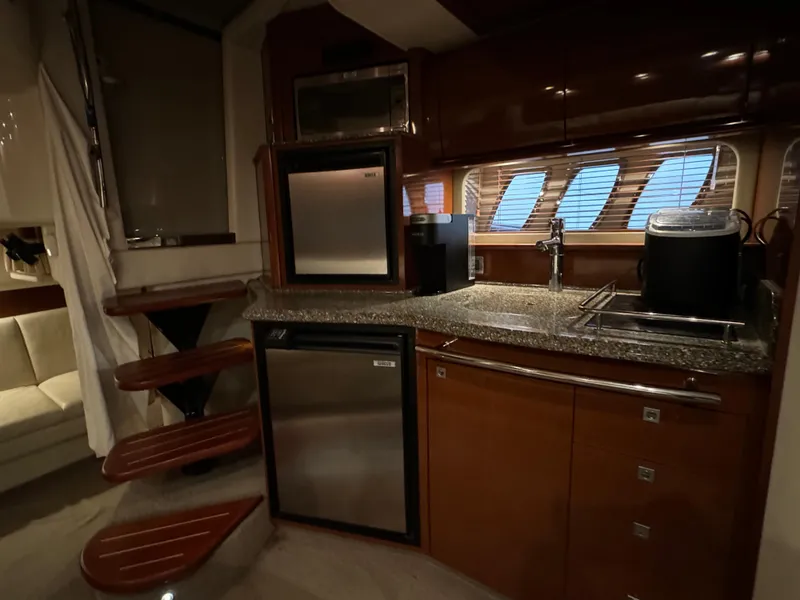 Slide: The Image of 2008 Sea Ray 38 Sundancer kitchen with stainless steel appliances and wooden cabinetry. - 20