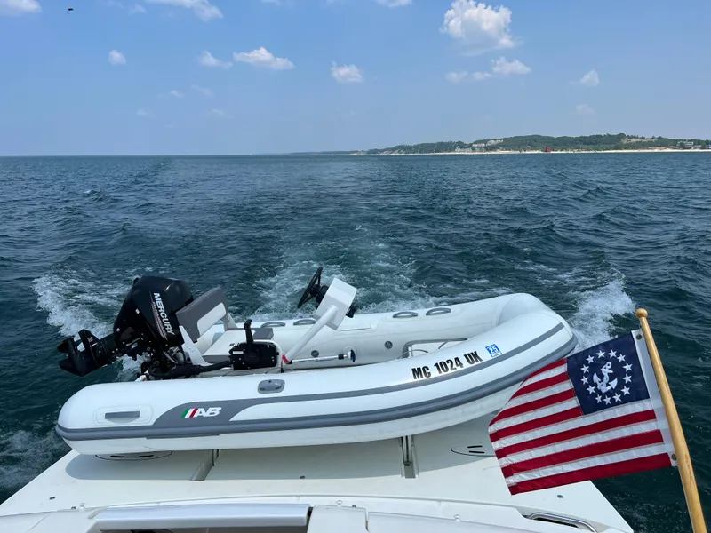 Slide: The Image of 2008 Sea Ray 38 Sundancer with dinghy and American flag on open water. - 32