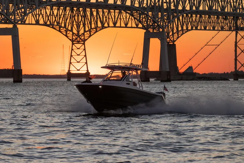 Slide: The Image of 2024 Solara 250 CW boat cruising under a bridge at sunset. - 4