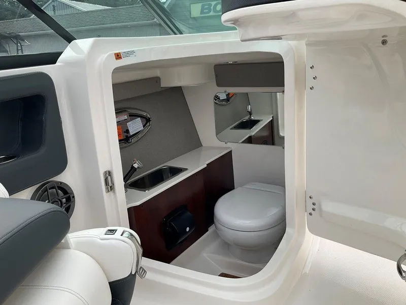 Slide: The Image of 2024 Chaparral 250 OSX boat interior with compact bathroom and sink. - 26