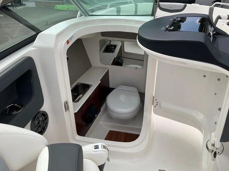 Slide: The Image of 2024 Chaparral 250 OSX boat interior with compact bathroom and modern amenities. - 28