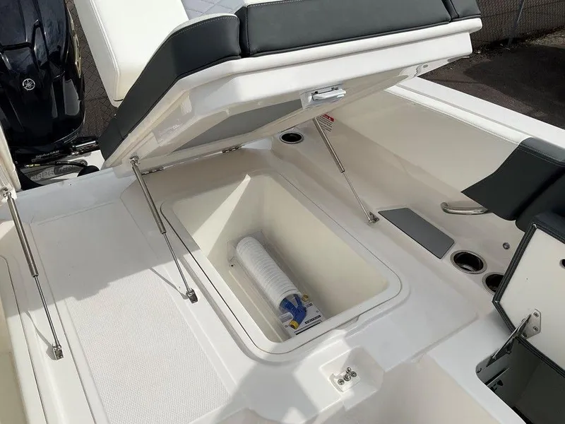 Slide: The Image of 2024 Chaparral 250 OSX boat storage compartment with open lid and visible accessories. - 38