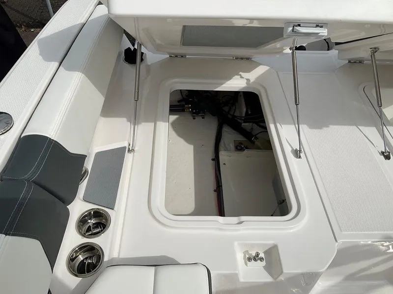 Slide: The Image of 2024 Chaparral 250 OSX boat storage compartment with open hatch and cup holders. - 39