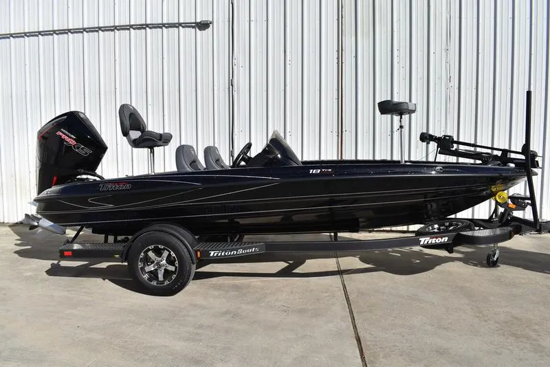 The Image of 2024 Triton 18 TrX bass boat on trailer, black exterior, side view. - 0