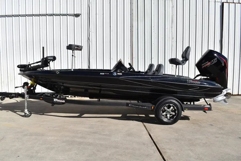 Slide: The Image of 2024 Triton 18 TrX bass boat on trailer, black exterior, parked outdoors. - 3