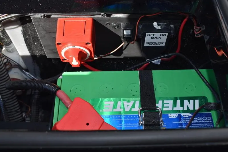 Slide: The Image of 2024 Triton 18 TrX boat battery compartment with Interstate battery and main power switch. - 31