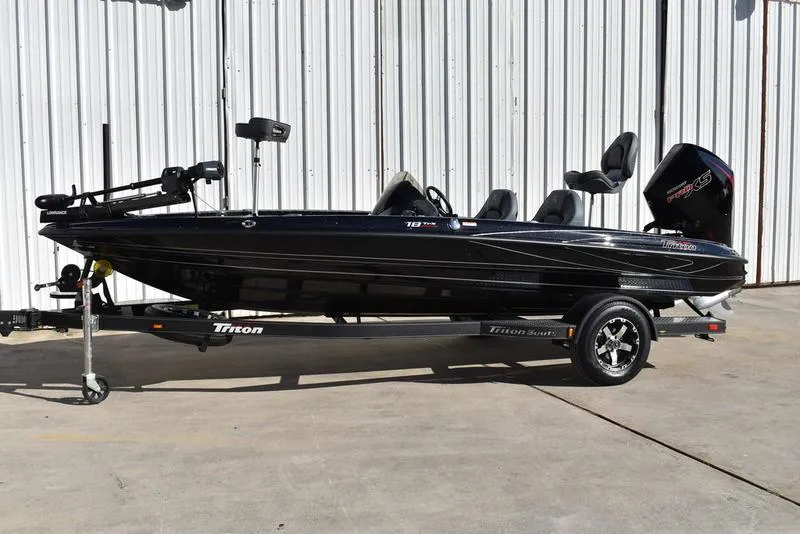 Slide: The Image of 2024 Triton 18 TrX bass boat on trailer, black exterior, side view. - 4