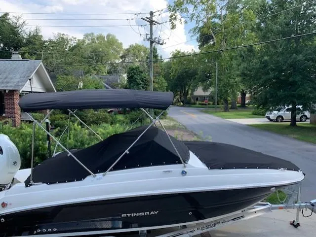 Slide: The Image of 2020 Stingray 201 DS boat with black cover and canopy on a trailer in a suburban neighborhood. - 18