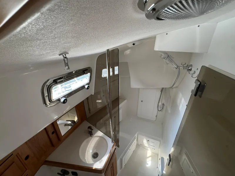 Slide: The Image of 2025 Tartan 365 yacht bathroom with sink, shower, and porthole window. - 18