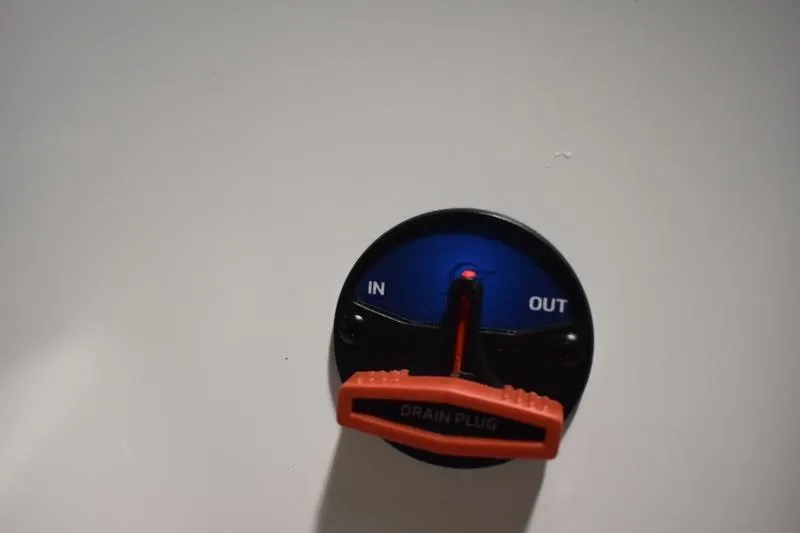 Slide: The Image of Control dial labeled "In" and "Out" with red drain plug on Triton 186 Allure 2024. - 127